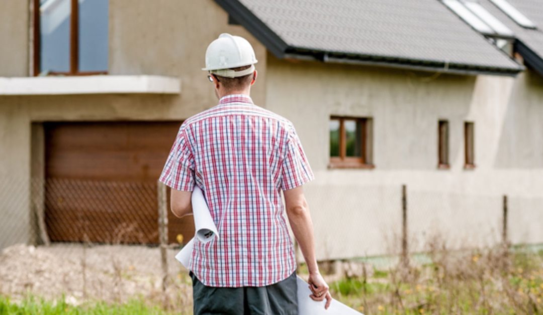 contractor wearing hard hat approaching home with fence after fire damage