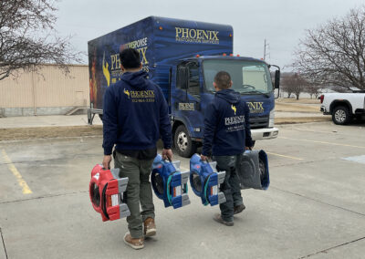 team members loading industrial fans into Phoenix Restoration truck