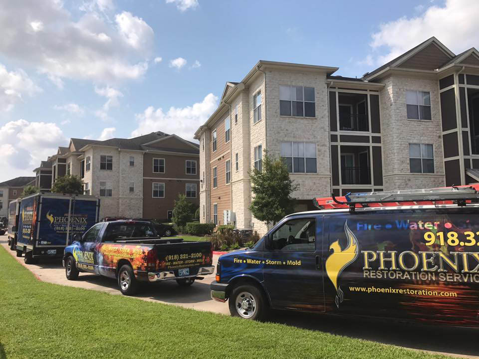 Phoenix Restoration vehicles parked outside residential buildings